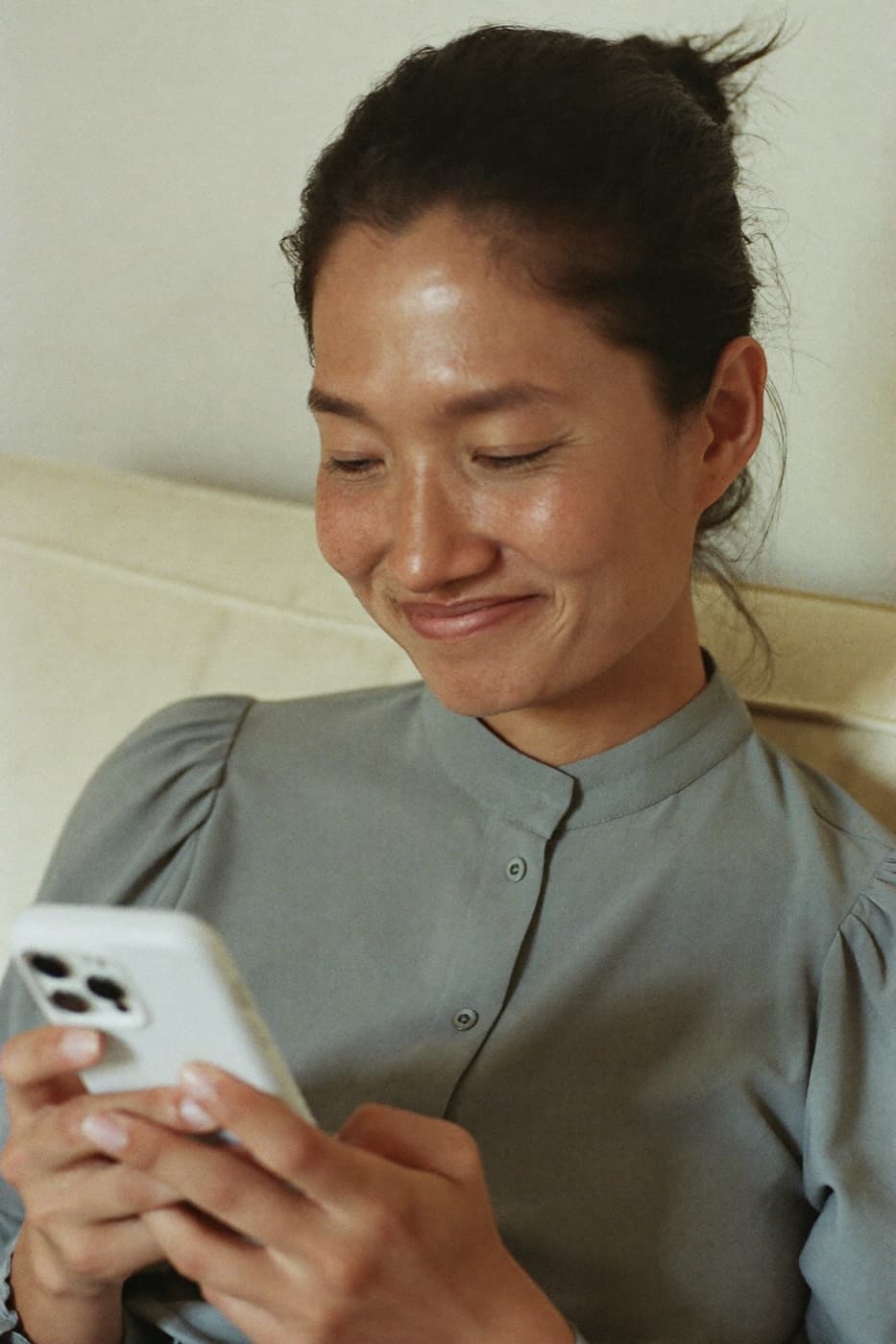 A woman smiling at her phone while checking in with her care team