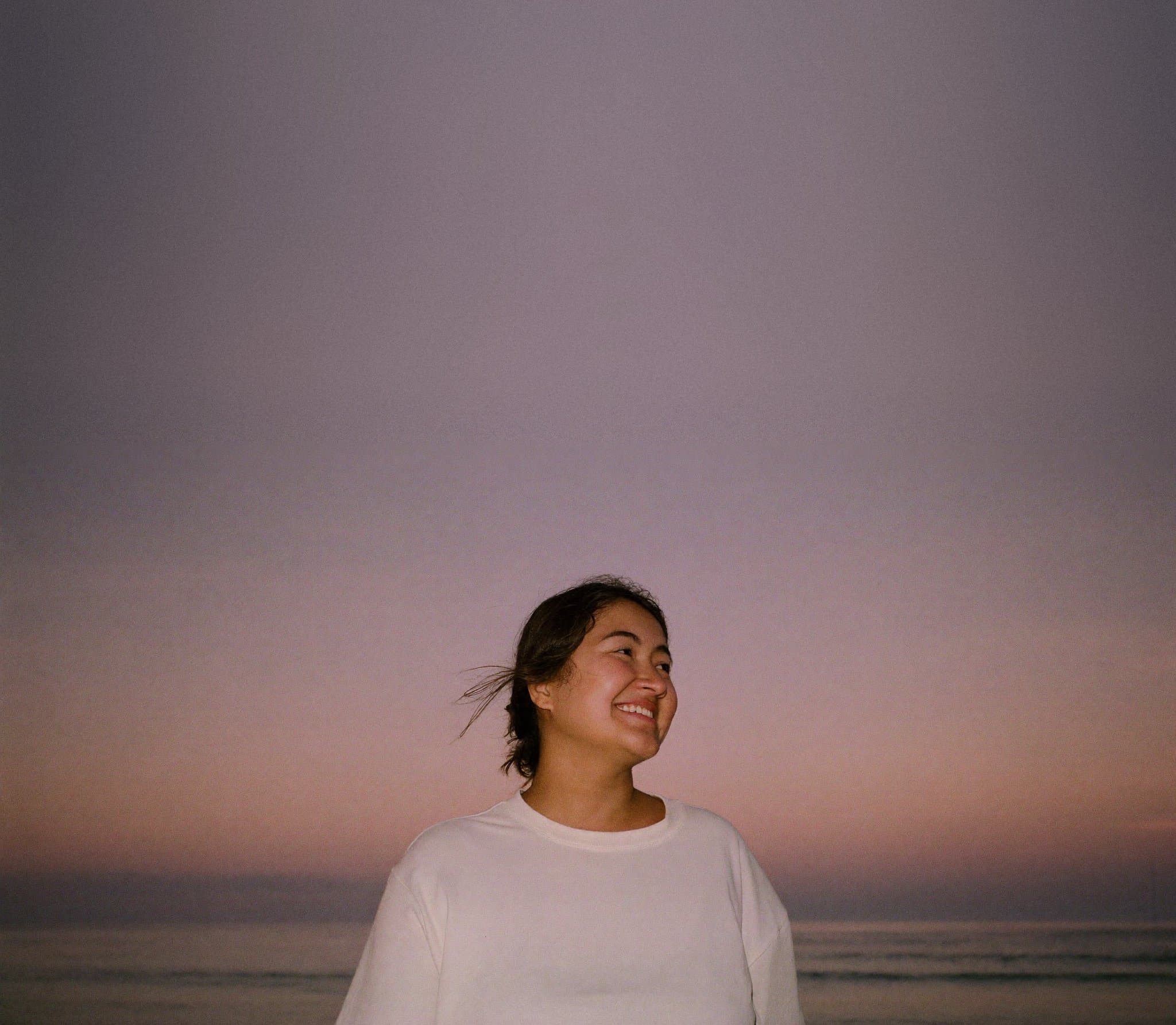 A woman laughing by the sea at dusk